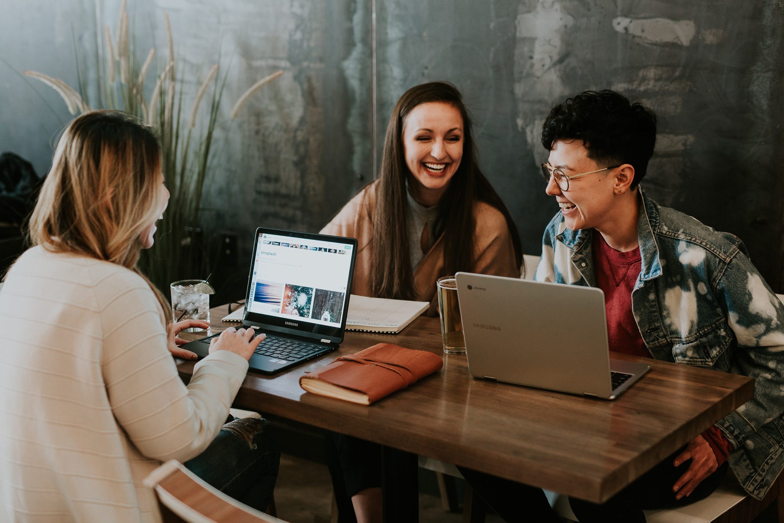 Junge, lachende Menschen arbeiten an ihren Laptops