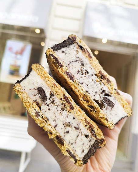 Frisch zubereitete Eis-Sandwiches mit Keksaußenlagen und Oreo-Keksstücken in veganem Eis, präsentiert vor dem Eingang von Veganista Wien